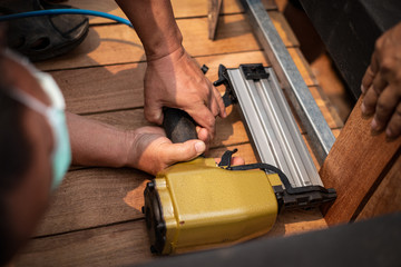 Hand man carpenter using air nail gun to complete wood table in garden