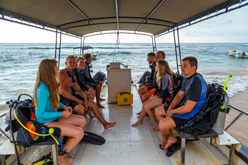 Scuba Divers team with diving equipment is sitting on boat in the Sri lanka sea and smiles