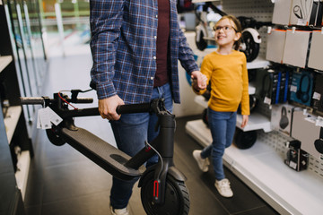Father and daughter buying electric scooter in tech store. © hedgehog94