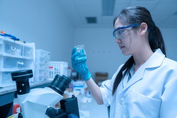 Asian scientist working in the lab,Researchers are research to find the results of the experiment,doctors are testing bloods to prevent and destroy new strains of the coronavirus through microscopy.