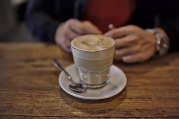 cup of cappuccino in a cafe in hands, coffee in a restaurant interior