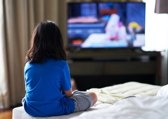 Girl sit on bed focus watching TV in room alone in family careless and TV addiction concept