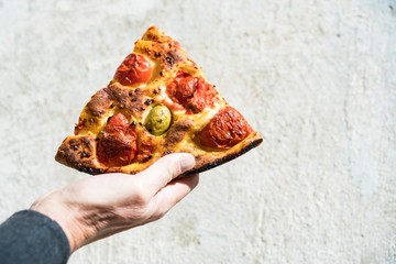 hand showing piece of pizza margherita
