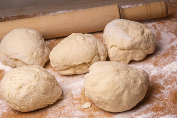 Balls of dough. Plywood cutting board, wooden flour sieve and wooden rolling pin - tools for making dough.