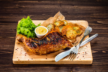Barbecue chicken thigh with baked potatoes on cutting board