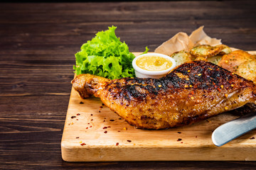 Barbecue chicken thigh with baked potatoes on cutting board