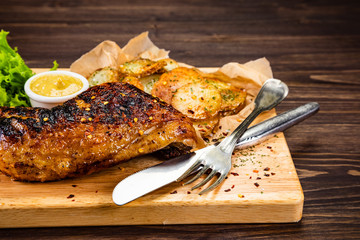 Barbecue chicken thigh with baked potatoes on cutting board