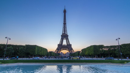 Fototapeta na wymiar Eiffel Tower day to night timelapse and people sitting on the grass in the evening in Paris, France