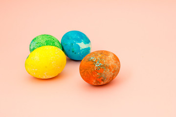 Four multi-colored Easter eggs on pink background top view, space for text. Concept happy easter day.