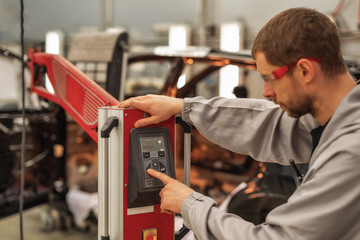 The worker of shop of coloring carries out drying of a varnish by means of a special lamp