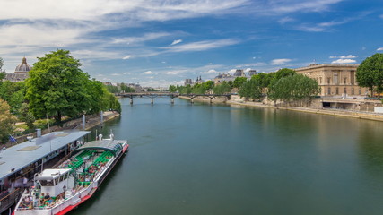 Fototapeta na wymiar Touristic boat passes below Pont des Arts and stop on boat station on Seine river timelapse in Paris.