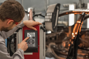The worker of shop of coloring carries out drying of a varnish by means of a special lamp