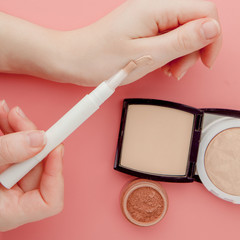 Woman's beauty blogger hands holding bottle and tube spa professional hi-end cosmetics on pink...