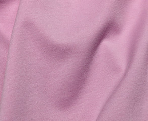 Textiles in cool pink color. The material folds randomly on a horizontal surface. Fabric sample.