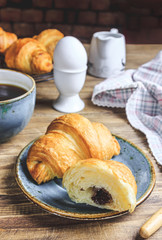 Coffee and croissant on rustic wooden table. French breakfast. Top view. Flat lay. Copy space.