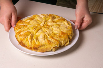 Apple pie, sprinkled with powdered sugar, stands on the table.