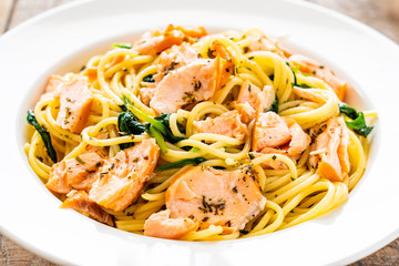 Pasta with salmon and spinach on wooden background