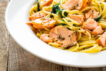 Pasta with salmon and spinach on wooden background