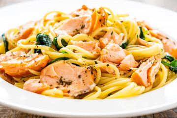 Pasta with salmon and spinach on wooden background
