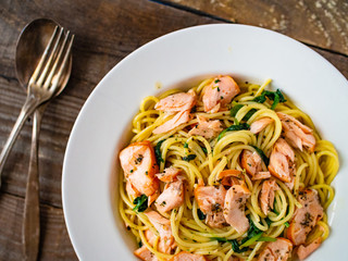 Pasta with salmon and spinach on wooden background