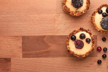 Healthy cereals muffins with berries and yellow cream on the wooden desk.