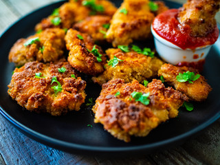 Fried chicken nuggets with ketchup on wooden table