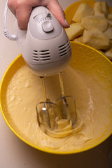 A woman mixes the ingredients for a pie in a yellow bowl with an electric mixer.