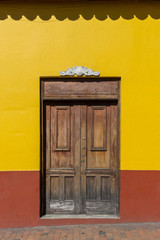 La Candelaria Wooden Double Door in Yellow and Red Wall. Bogota, Colombia.