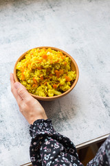 Basmati curry Indian rice with vegetables. Vegan and vegetarian healthy food. Woman holds rice bowl.