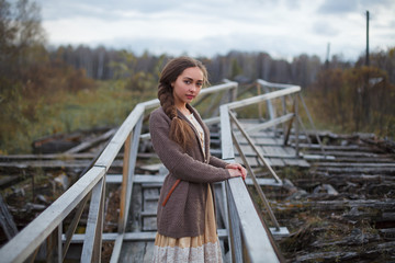 girl in vintage dress stands on a bridge