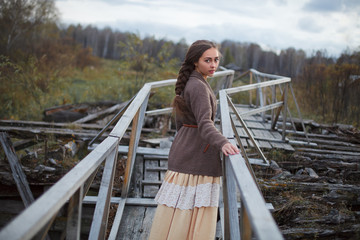 girl in vintage dress stands on a bridge