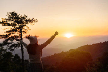 Young woman traveler looking at sunrise over the mountain