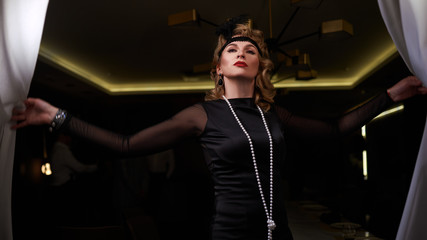 1920s retro style. Old times, A beautiful happy young actress woman in a dress plays a role in a...