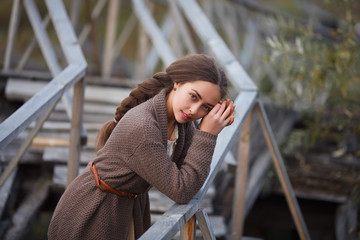 girl in vintage dress stands on a bridge