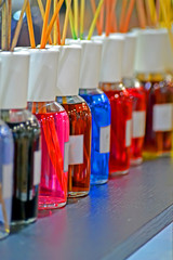 abstract rainbow cosmetic bottles line on the wooden table with sticks heap, aroma color
