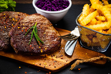 Barbecue beef steak french fries and vegetables on black stone 