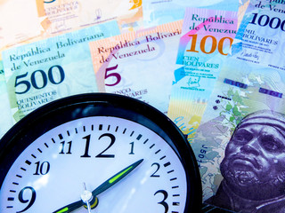  Finance: Venezuelan money and a black watch with a white dial.