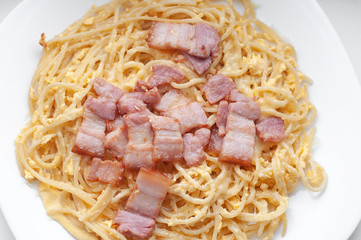 Pasta with bacon in a creamy sauce with cheese, top view
