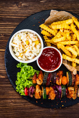 Grilled shashliks and French fries on black stone plate