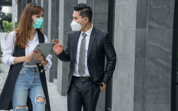 Asian male and female workers talking together wear protective masks prevent PM 2.5 and corona viruus or covic 19 at model new office .Concepts health and prevention of serious laxative diseases.