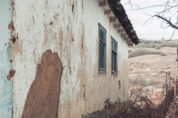 Old abandoned clay house with cracked walls 