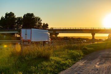 truck with refrigerated semi-trailer driving on the highway at sunset