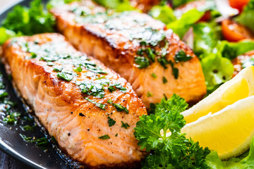 Fried salmon steaks with vegetables on wooden table