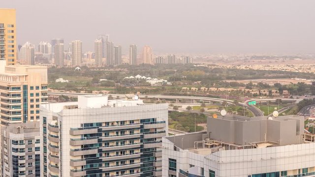 Dubai Marina towers with Golf Course and cityscape of Gereens and tecom districts at the background aerial timelapse. Traffic on road with junction