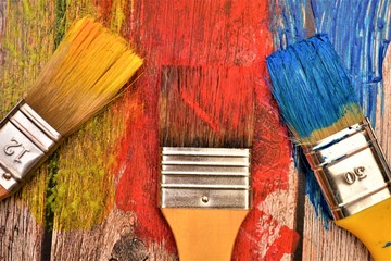 tre pennelli per colorare con colori rosso giallo blu con sfondo di legno