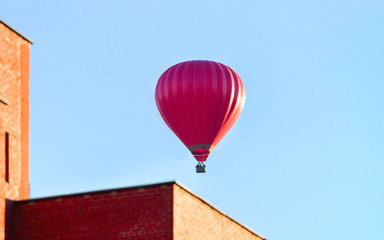 Fototapeta na wymiar Red air balloon flying over residential house building