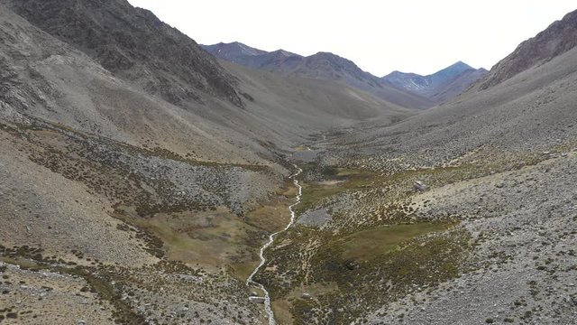A reverse flight view inside Andes mountains at Limari Valley, south Atacama. An amazing wild scenery. Arid idyllic valleys with green farm fields feed in by the river at the bottom of the valley
