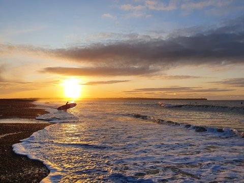 Surfer in the sunrise heading out tramore ireland
