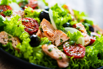 Salmon salad - roasted salmon and vegetables on wooden background