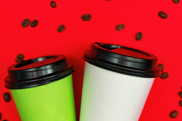 Top view of  paper dispocable coffee cups on red background with coffee beans.